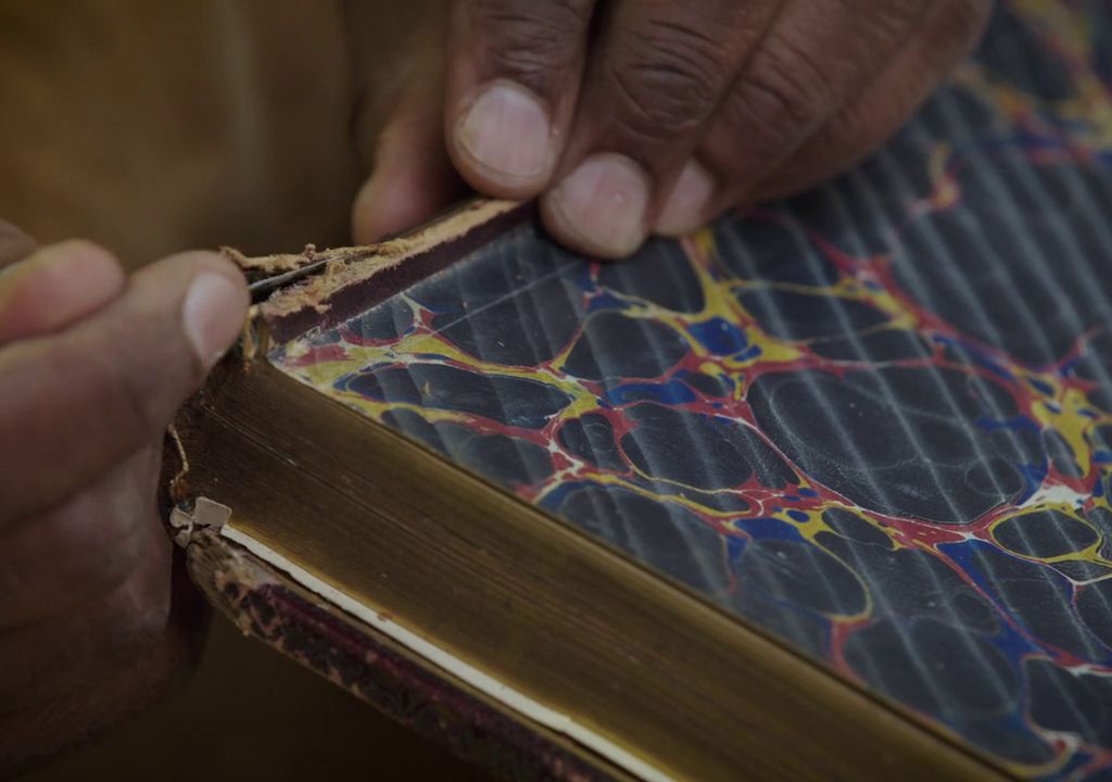 Close up of hands repairing a book spine.
