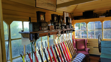 Small shed with lots of big windows and a line of large coloured signal levers.