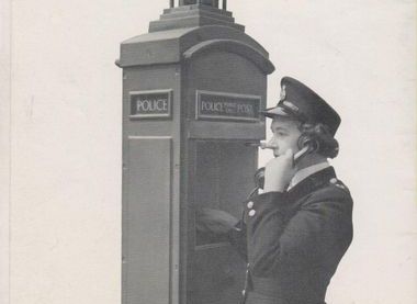 Woman Police Officer using a street police telephone post 
