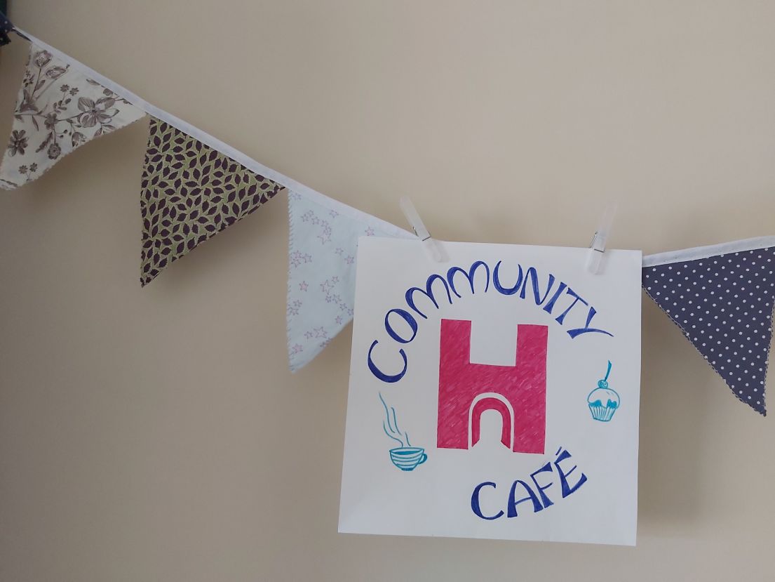 Different coloured and patterned fabric bunting, with a Community Cafe sign.
