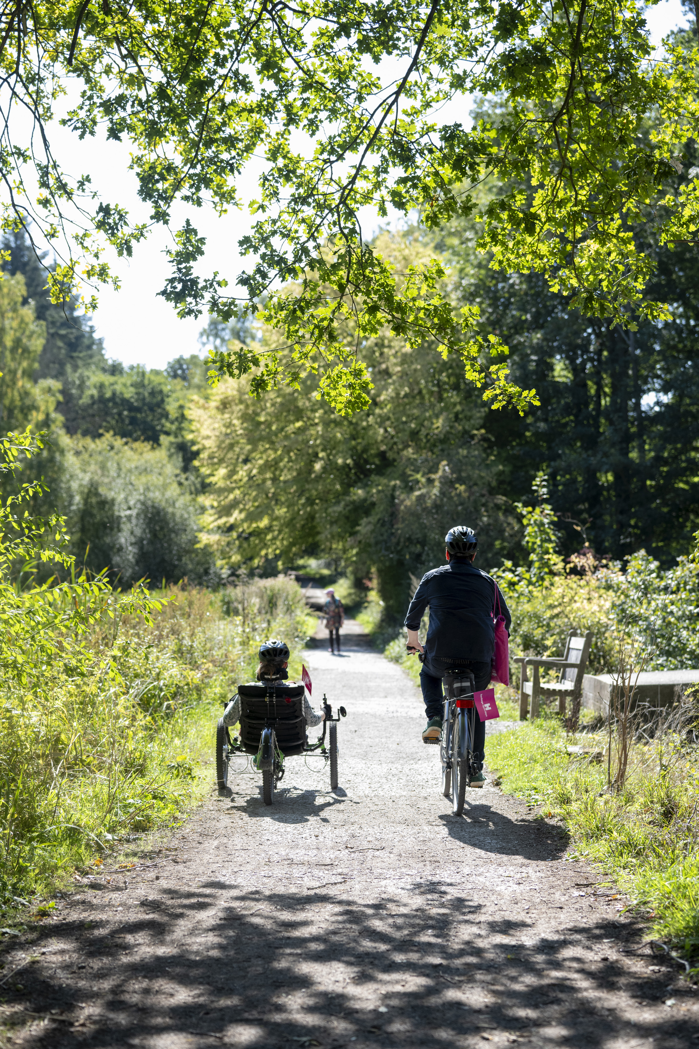 Two people cycling on country path, one riding a recumbant tricycle.