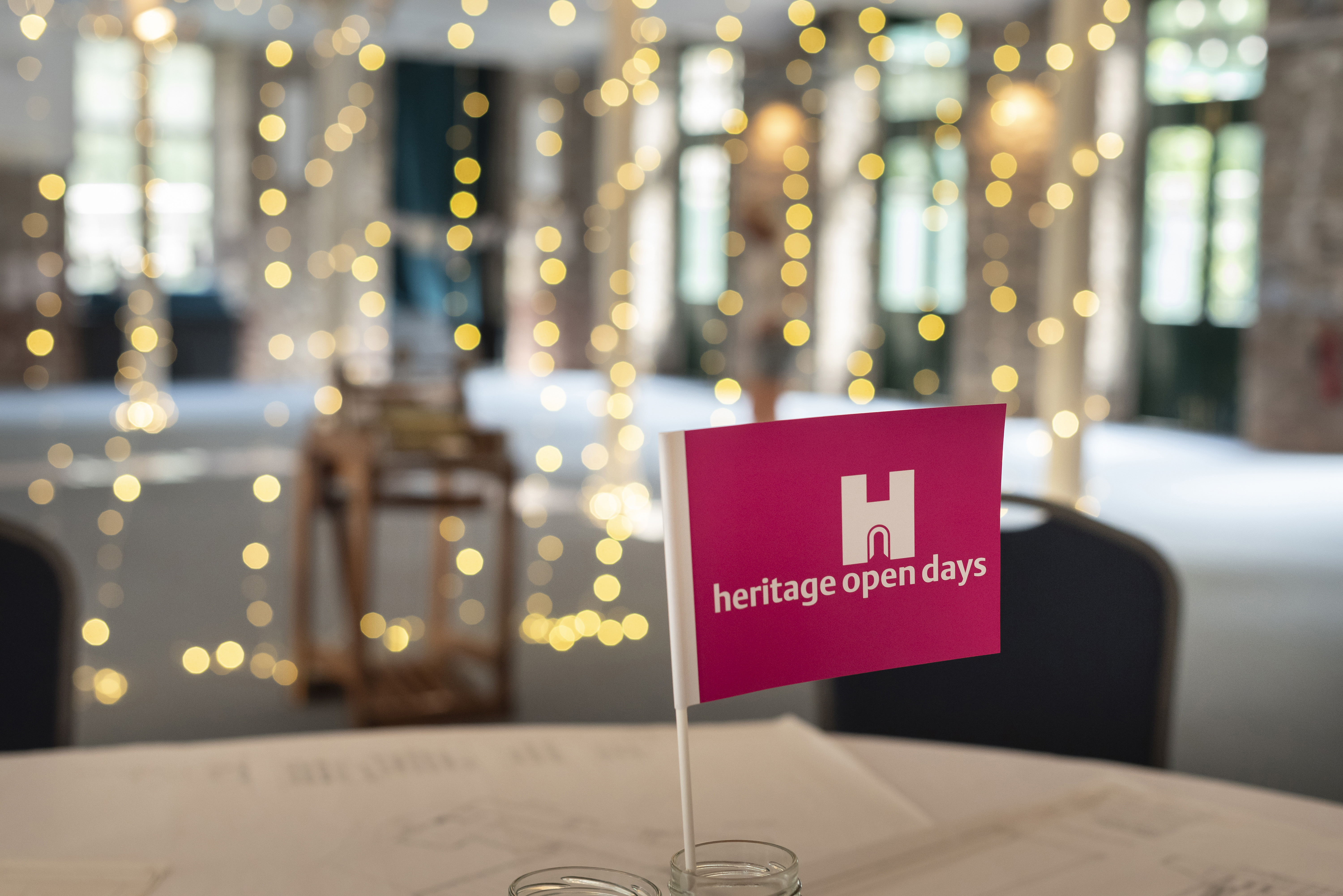 Small pink flag upright on a table in a blurred room with fairy lights in the background