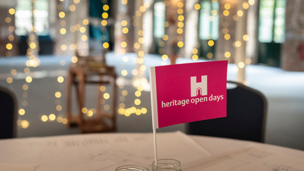 Small pink flag upright on a table in a blurred room with fairy lights in the background