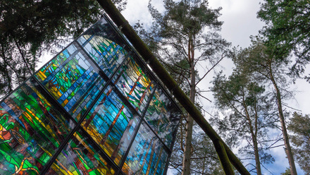 A close up of a stained-glass style art piece with trees behind it.