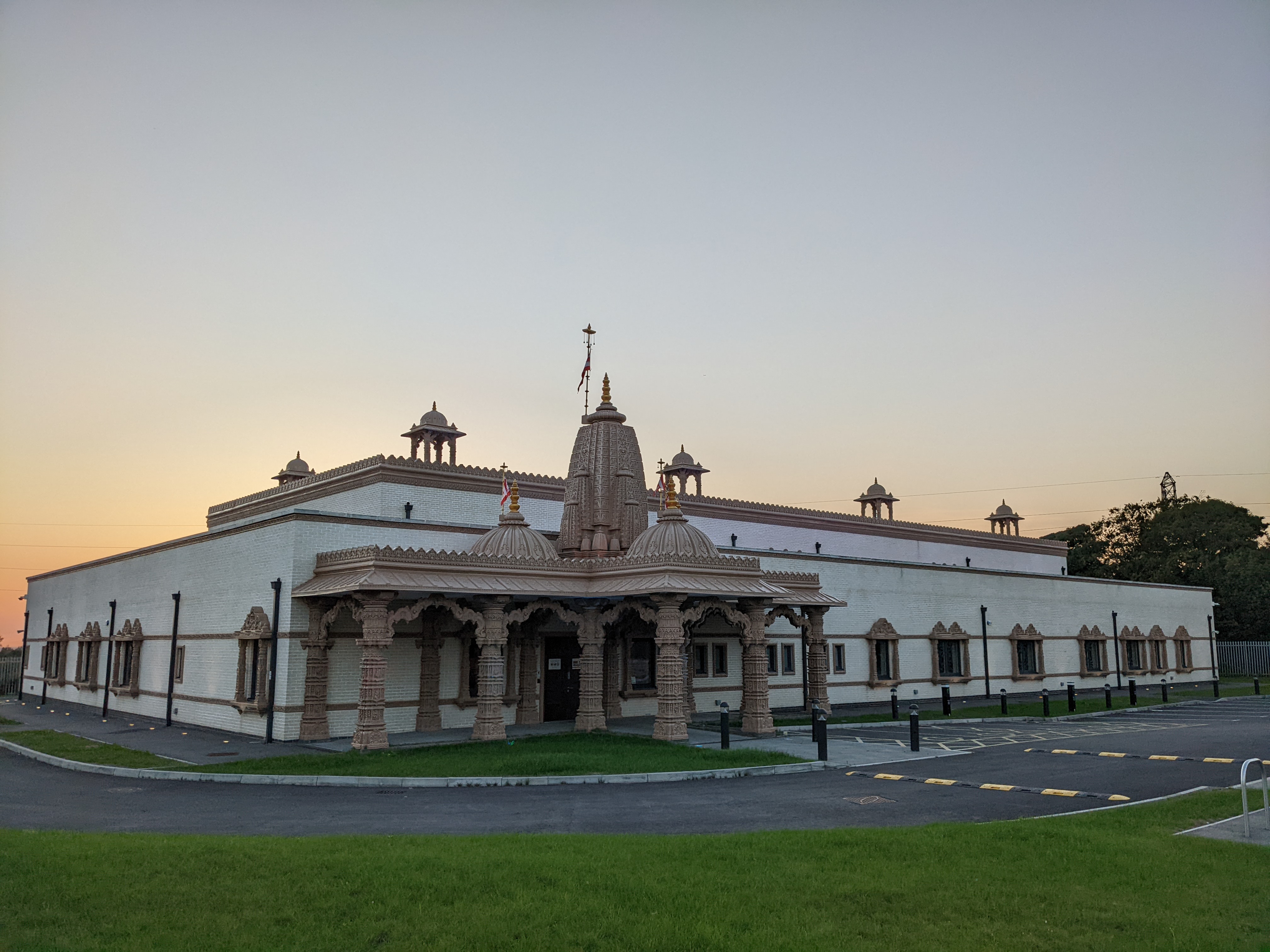 Large low box like white building with stone colonnaded entrance and temple pinnacles.