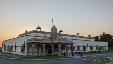 Large low box like white building with stone colonnaded entrance and temple pinnacles.