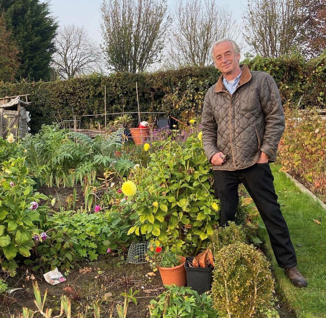 Man stood on grass path bordering allotment plot