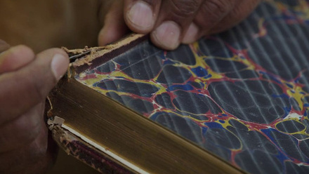 Close up of hands repairing a book spine.