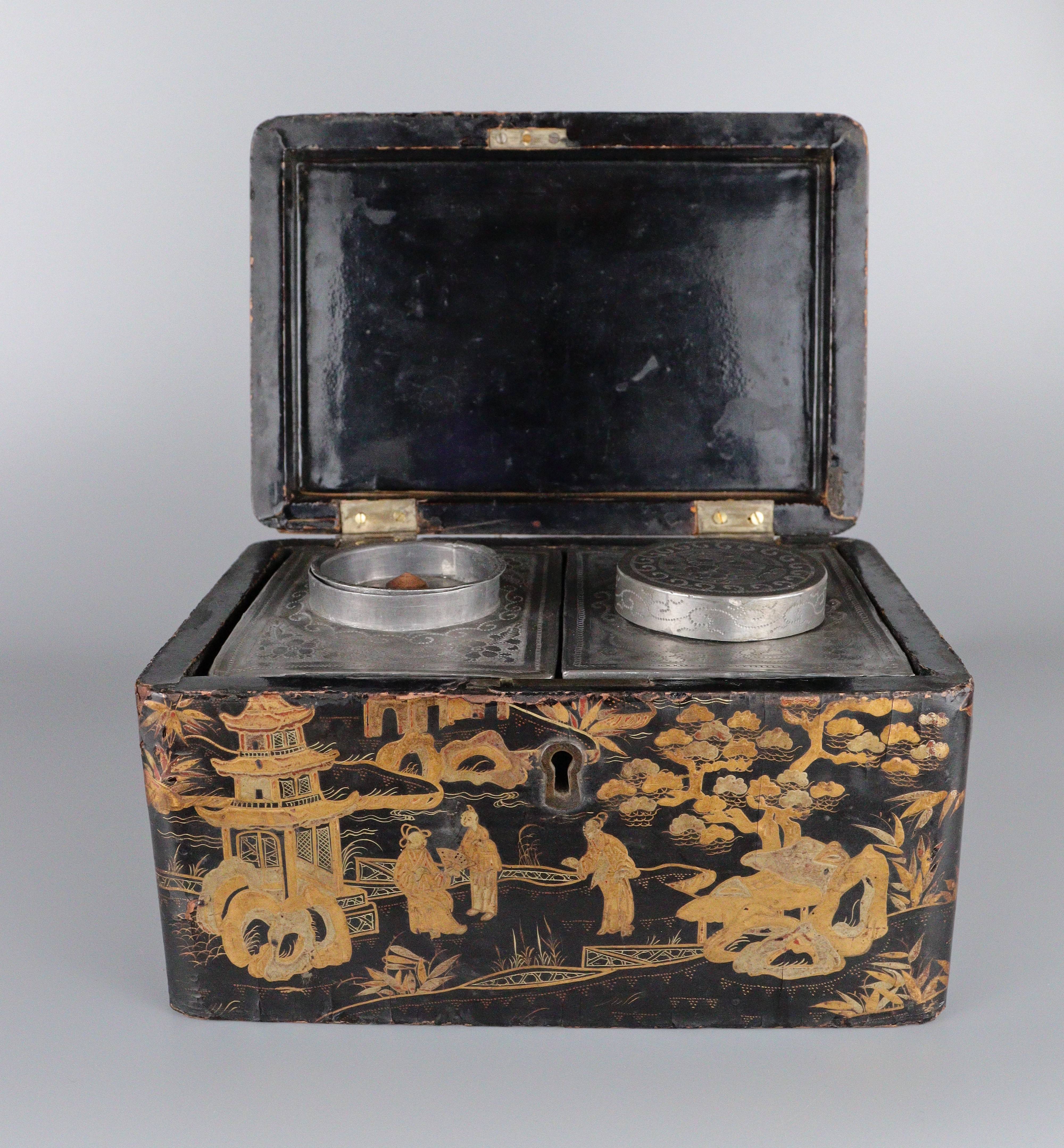 Black lacquer box with gold decoration, hinged lid pushed up revealing two metal canisters inside. 