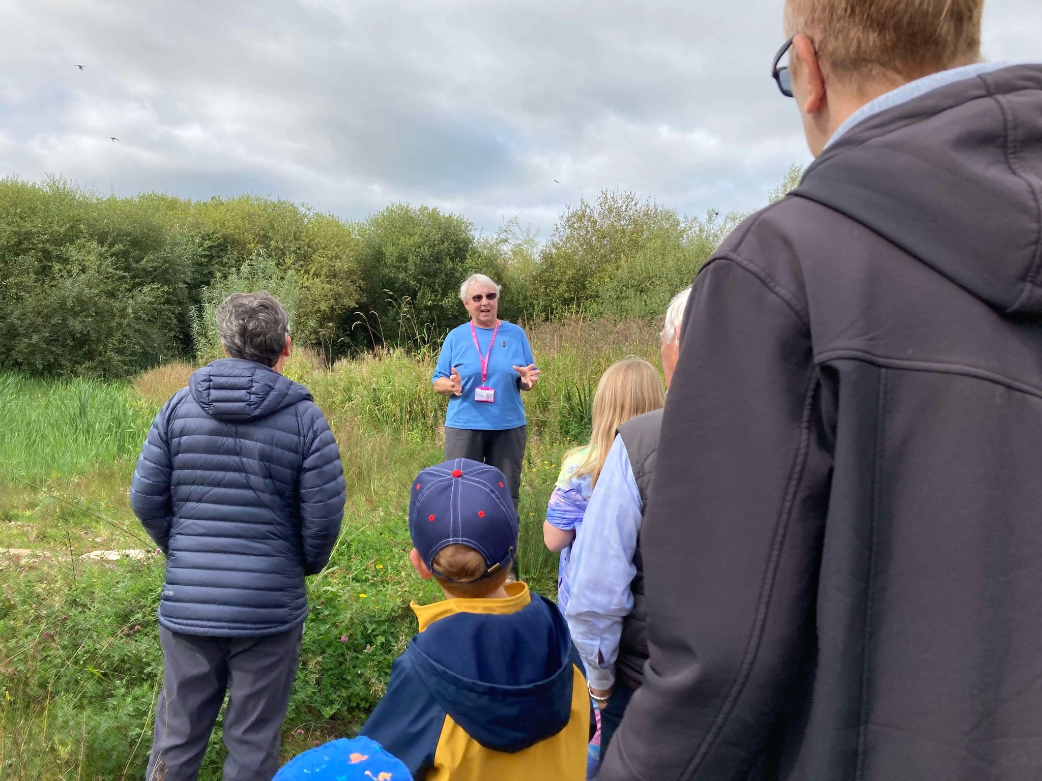 Volunteer talking to a group in grassland.