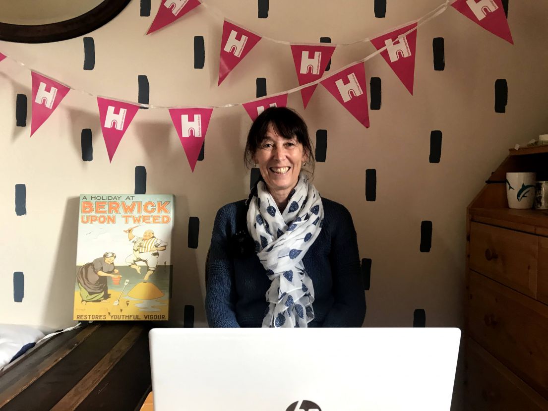 Woman sat in front of a computer with festival bunting hung up behind her