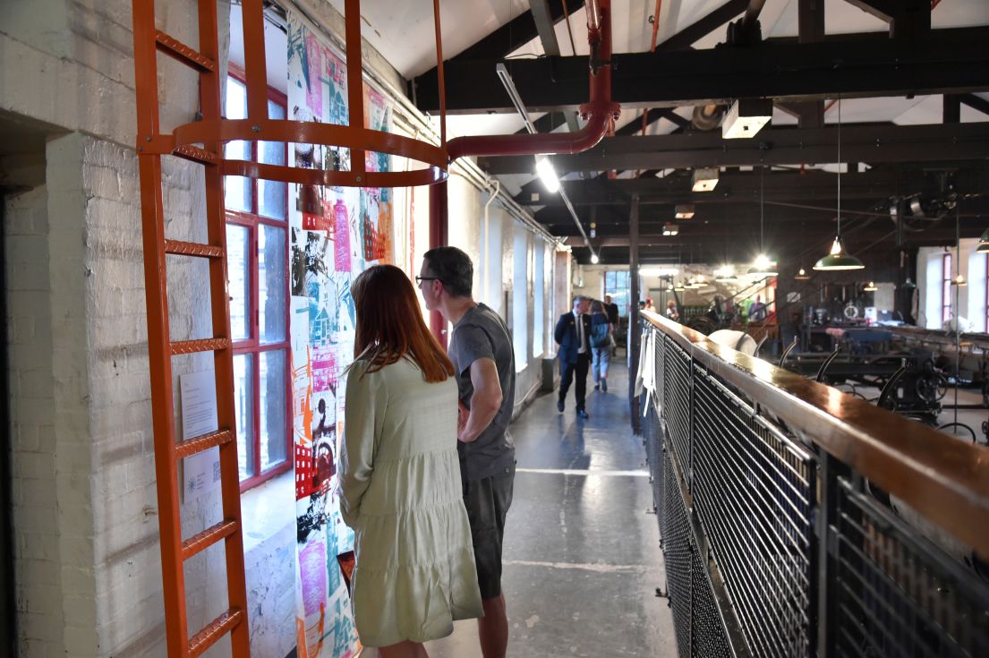 A man and women looking at a displayed piece of bright art.