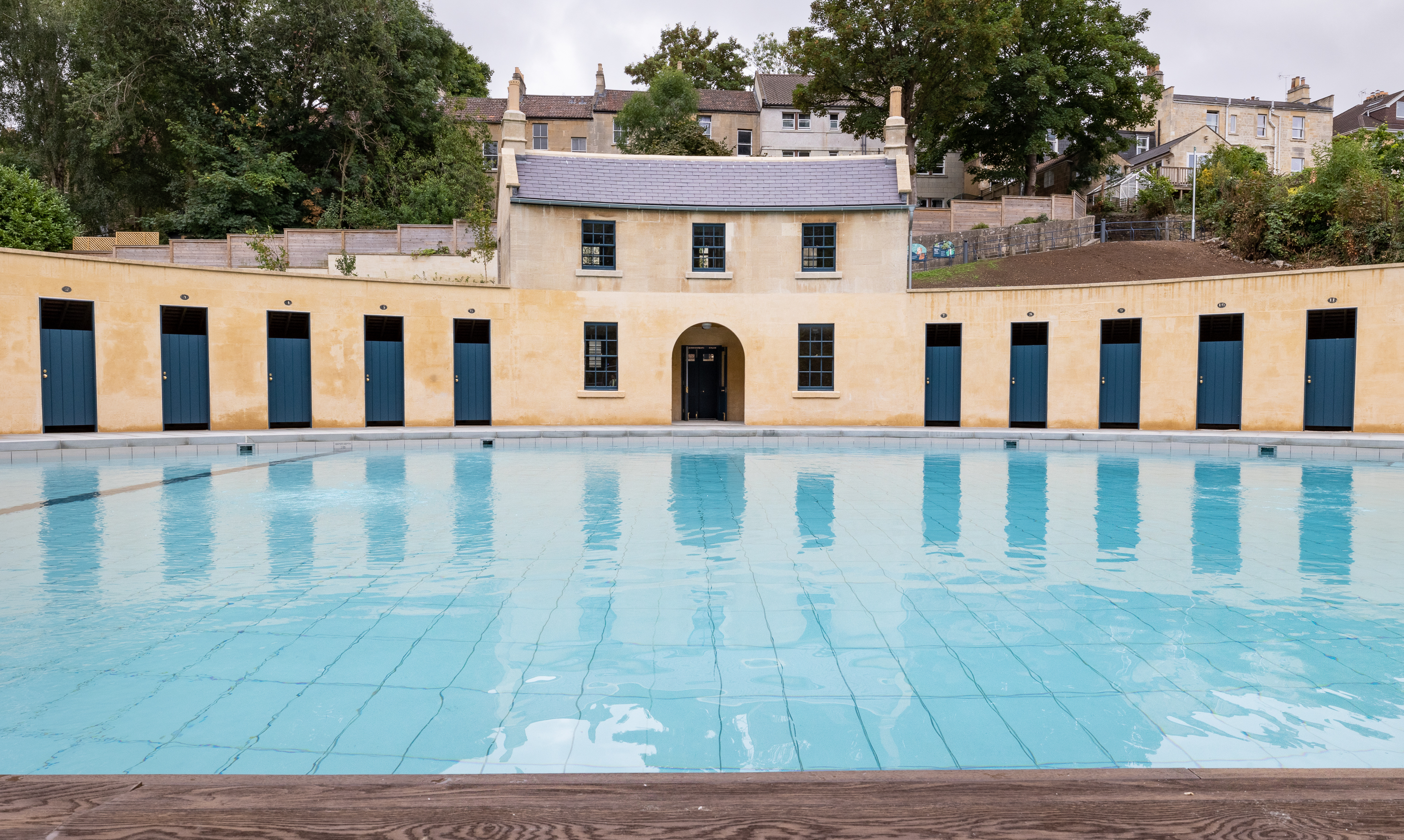 Two story building with single story wings arcing to each side round a blue pool.