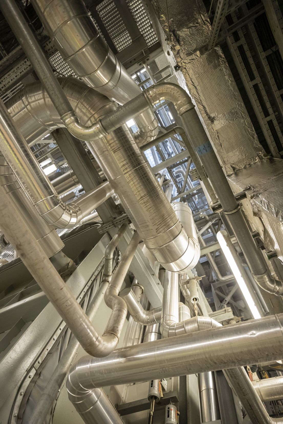 Looking up in a large building, the view obstructed by various silver metal poles going in different directions.