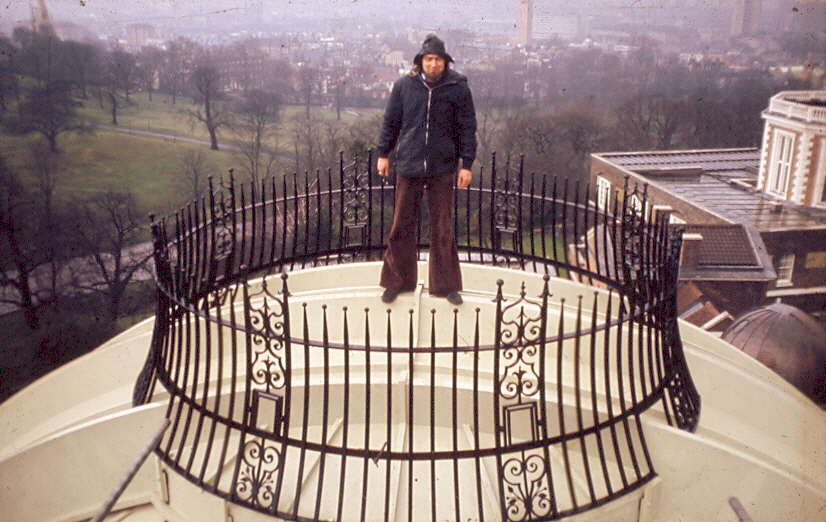 Person standing atop a domed roof within circle of metal railing.