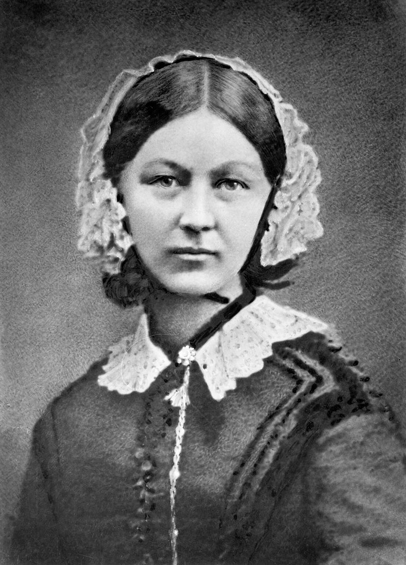 A black and white photo of a women in Victorian dress and bonnet.