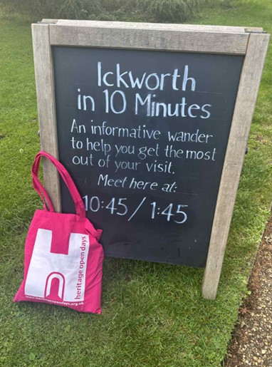 Branded pink bag leaning against chalkboard highlighting tour times.