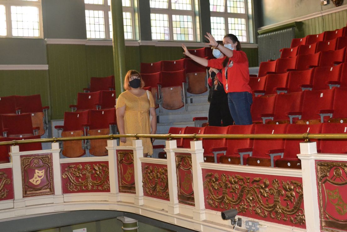 Three people, wearing face masks, pictured standing within the red velvet seat of the circle at Y Theatre Leicester.