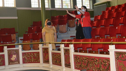 Three people, wearing face masks, pictured standing within the red velvet seat of the circle at Y Theatre Leicester.