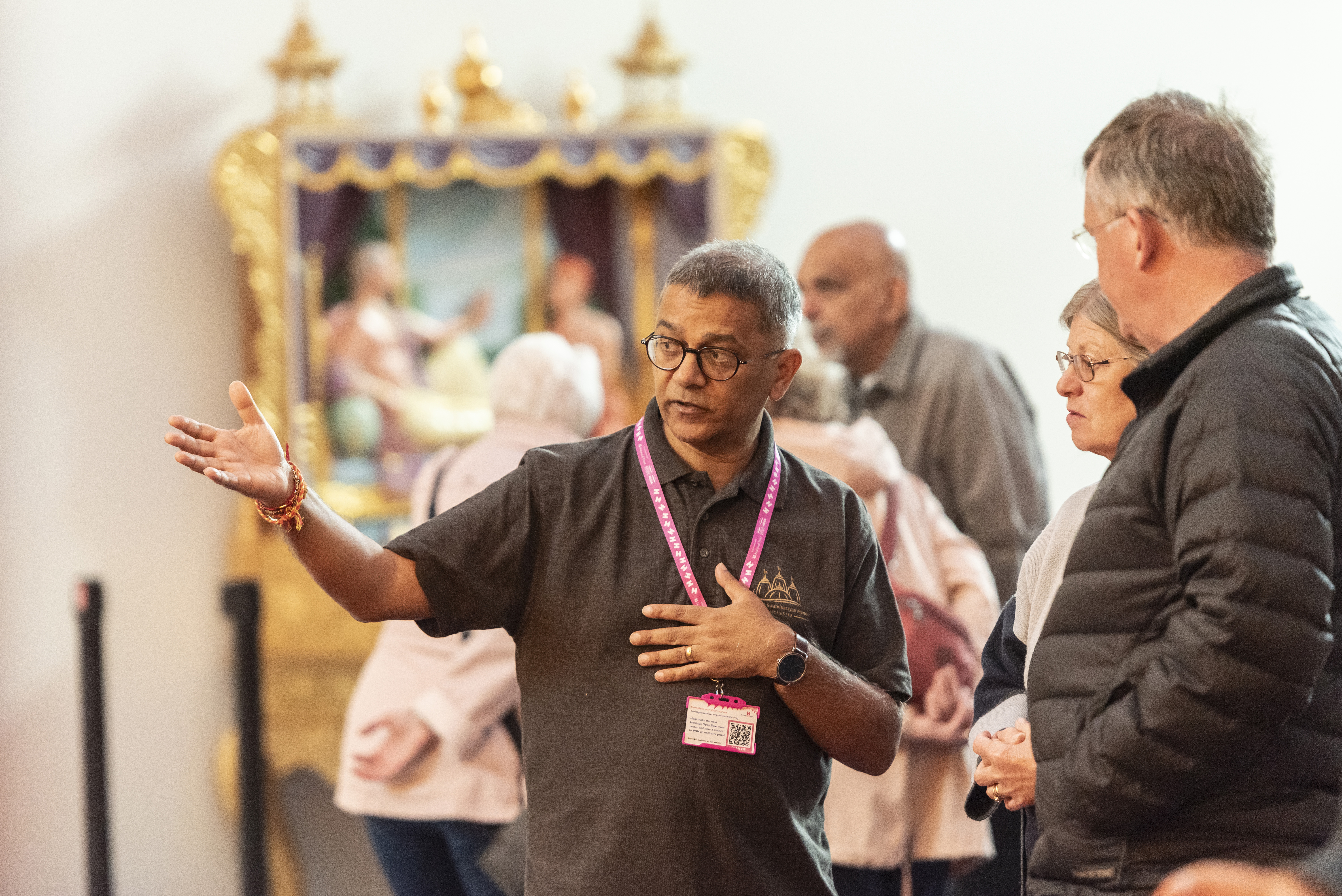 Man talking to a couple with a shrine in the background.
