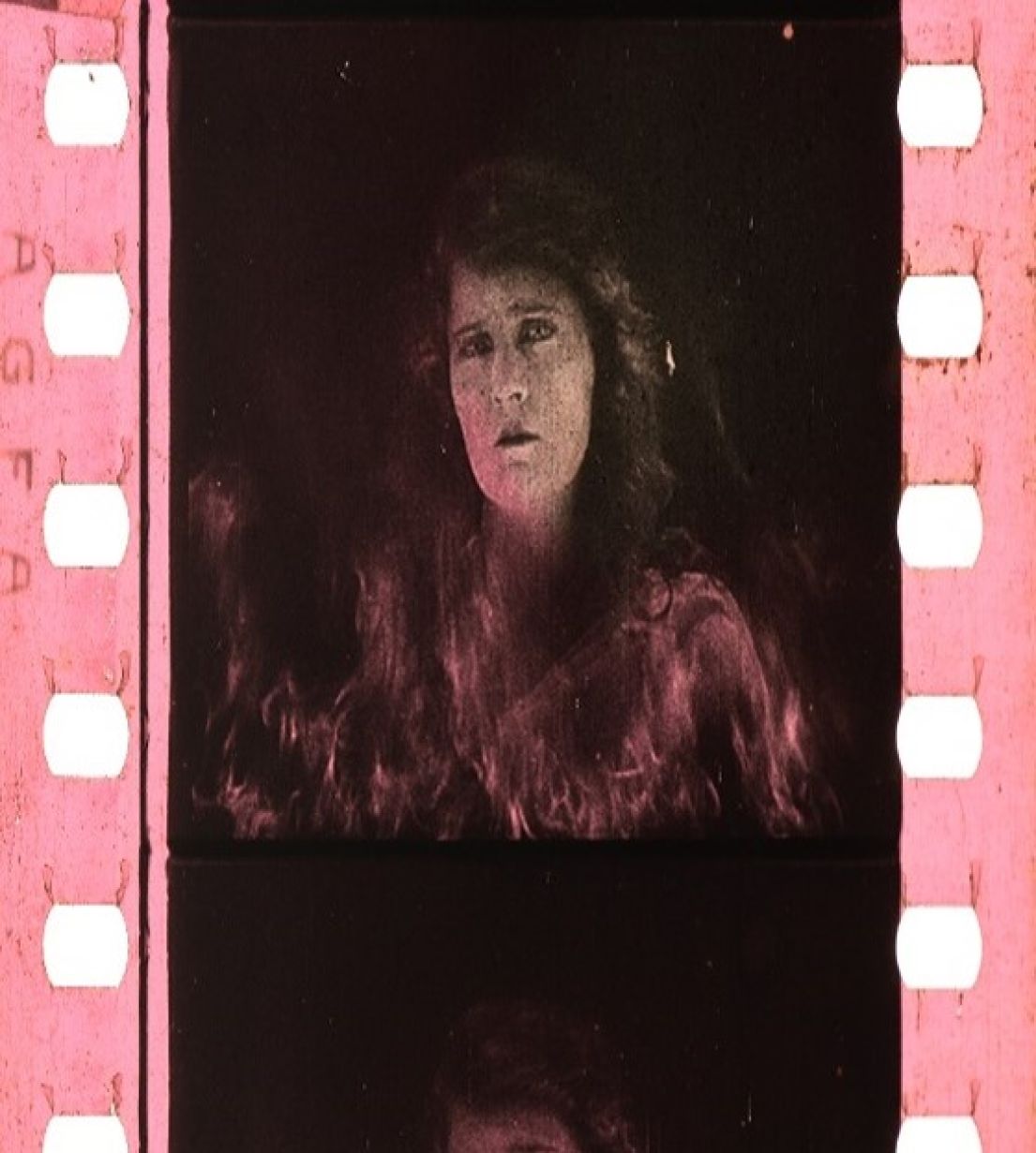 Section of film negative showing a woman's ghostly face surrounded by flames.