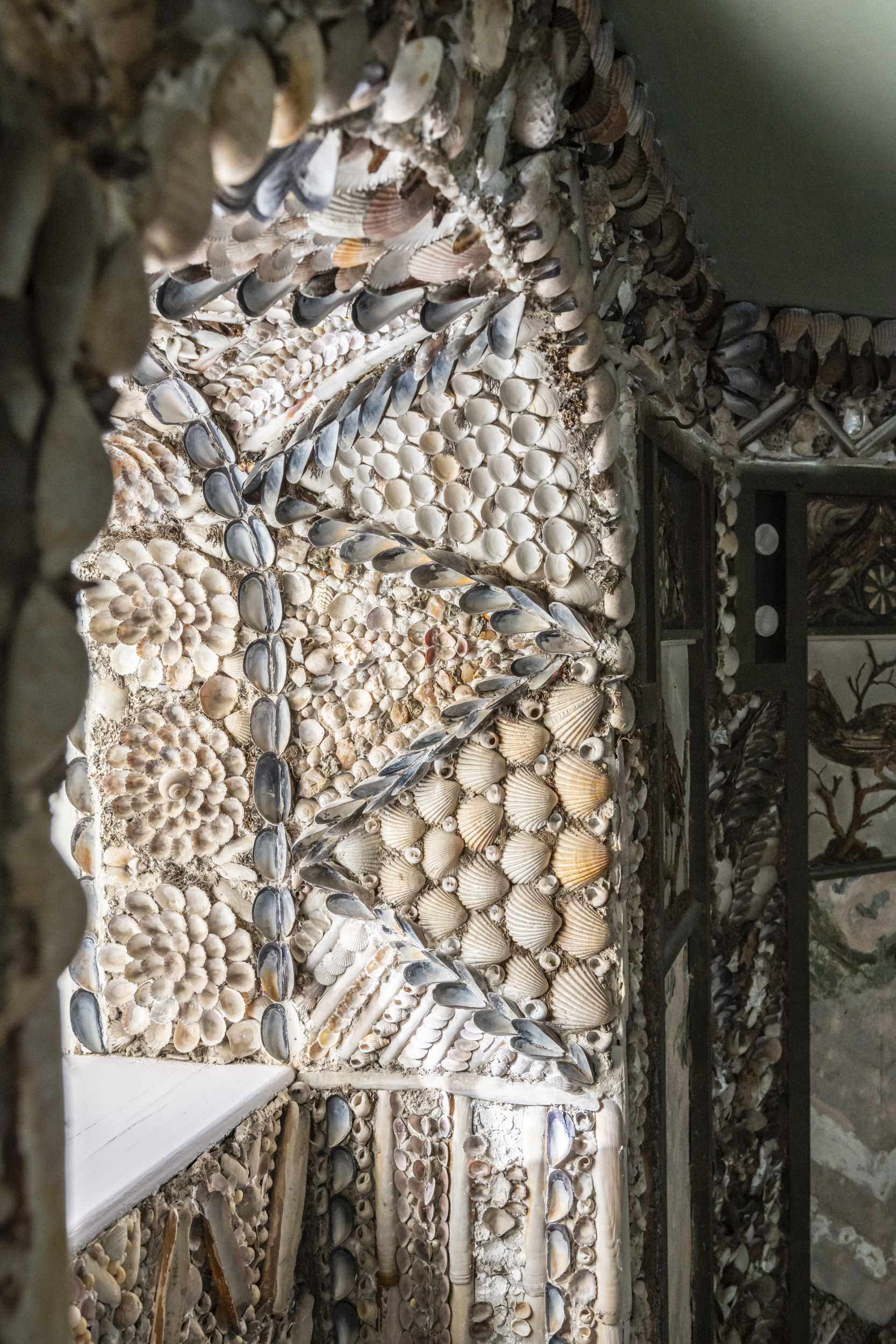 An arched window covered in shells.