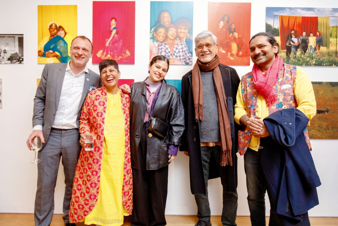 Five individuals standing in-front of brightly coloured pieces of art.