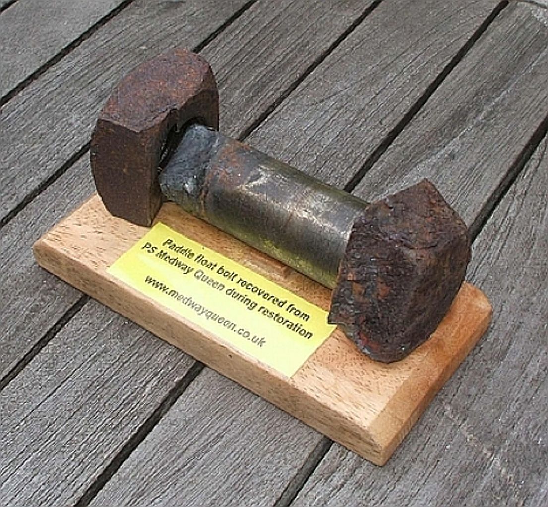 A paddle wheel bolt which has been mounted on a wooden plaque.