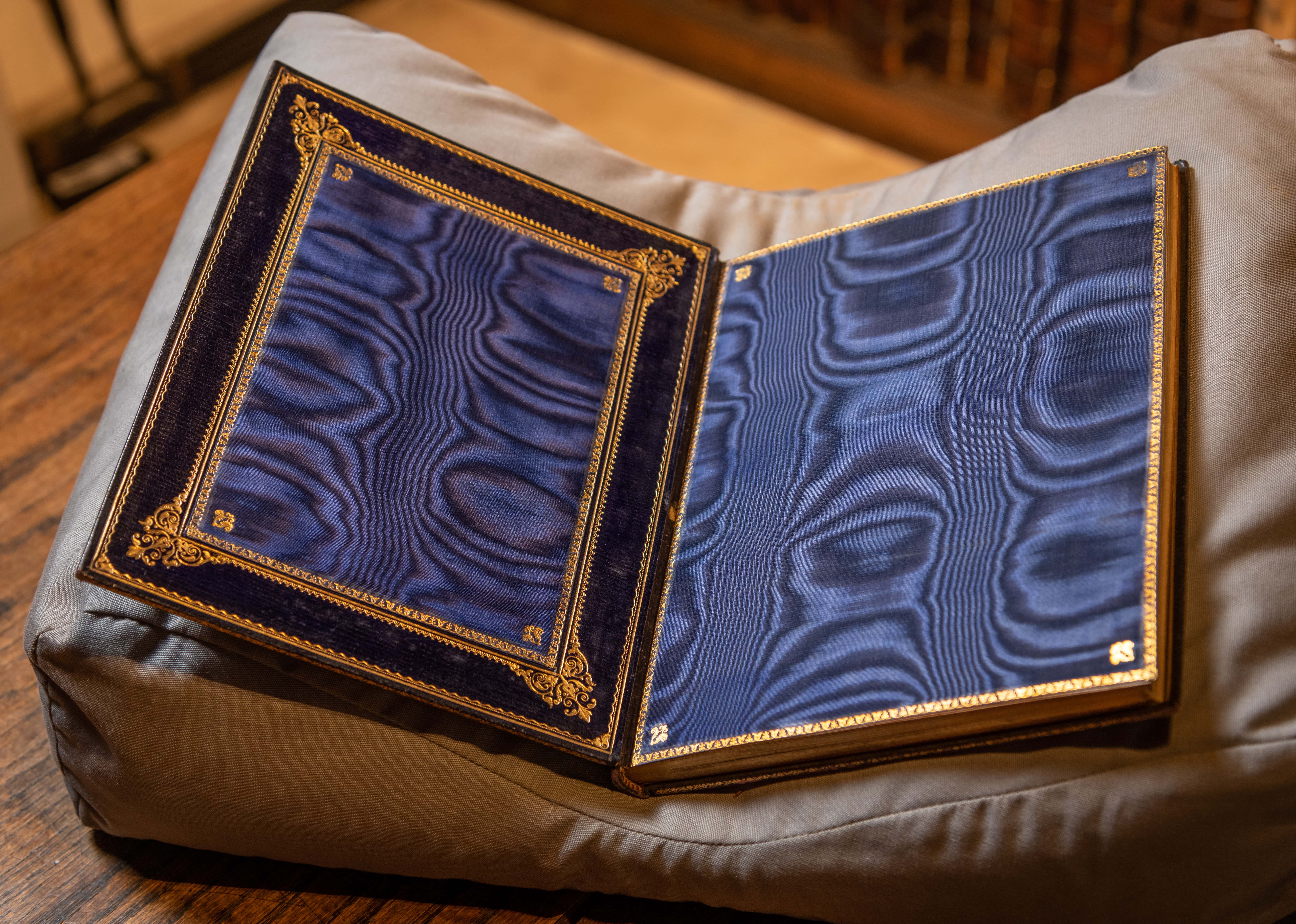 Book lying open with gilt edges and a blue silk lining.