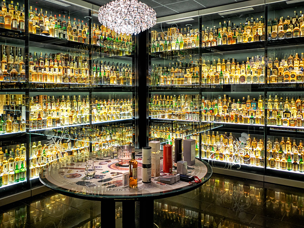 Corner of room lined with glass cabinets full of whisky bottles.