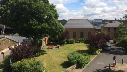 A drone taken picture showing the site of the Unitarian chapel - the one story building overlooked by tall bushy trees.