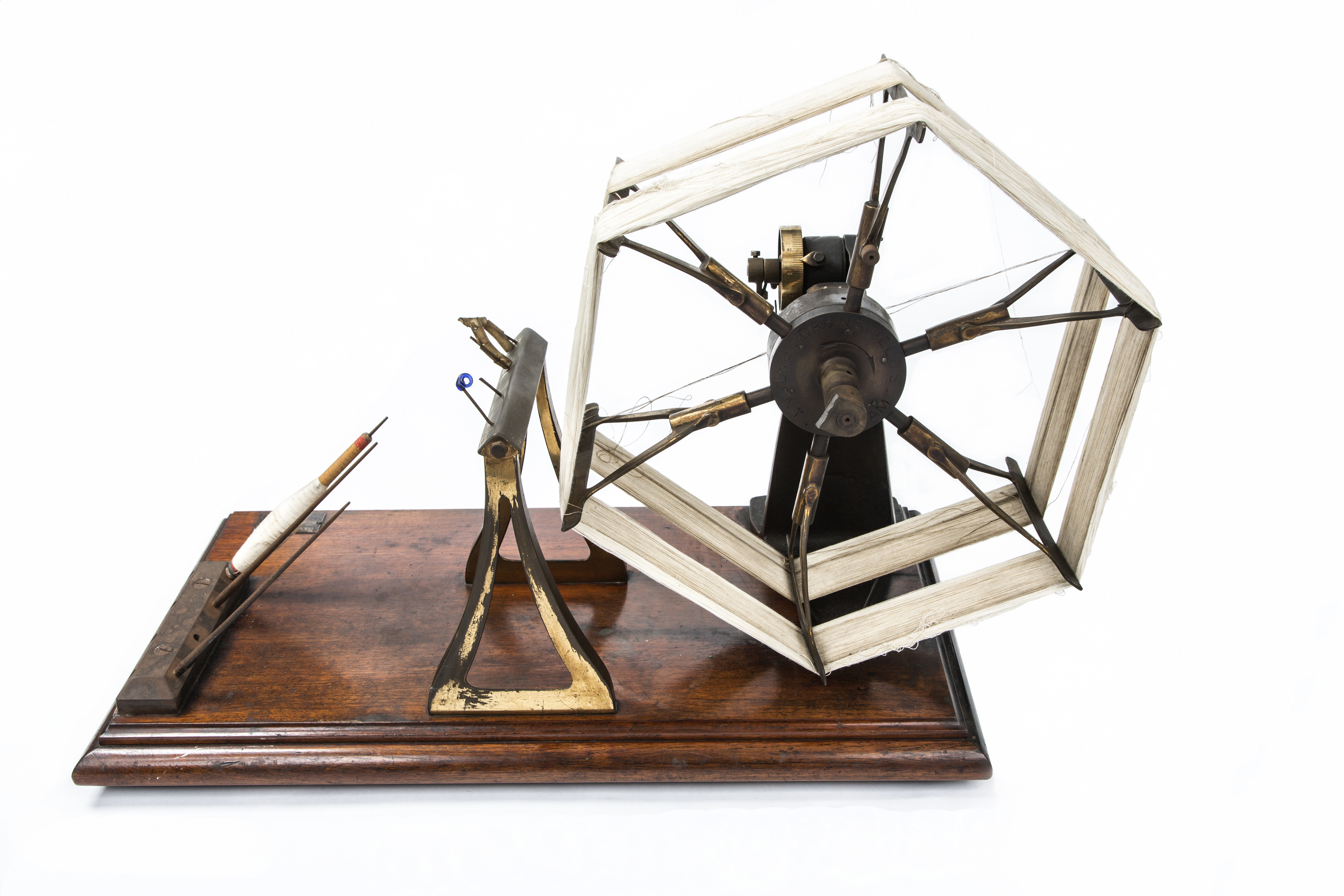 Small model of a hexagonal wheel with bands round it on a wooden stand.