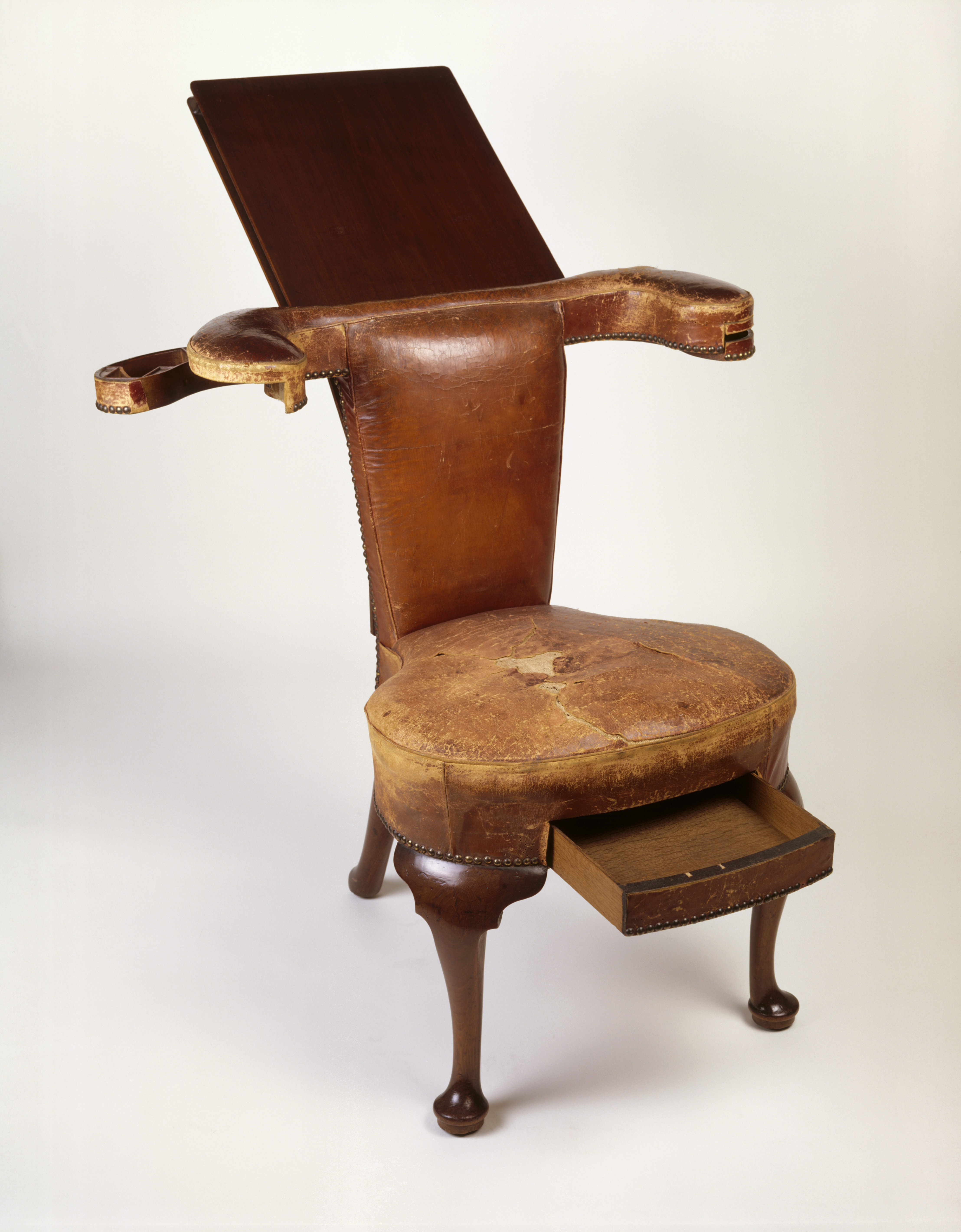 Small leather chair with a drawer in the seat and a book rest at the top.
