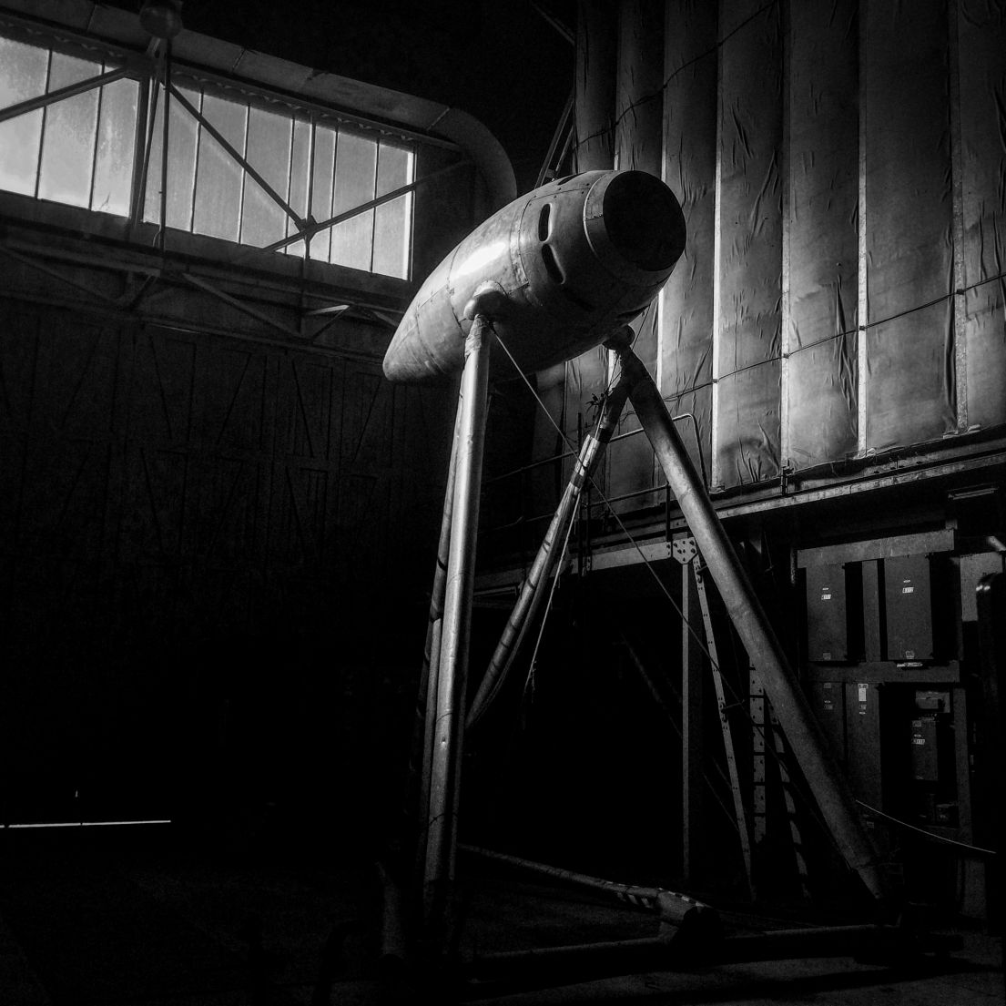 Black and white photograph of an aviation object in a hangar.