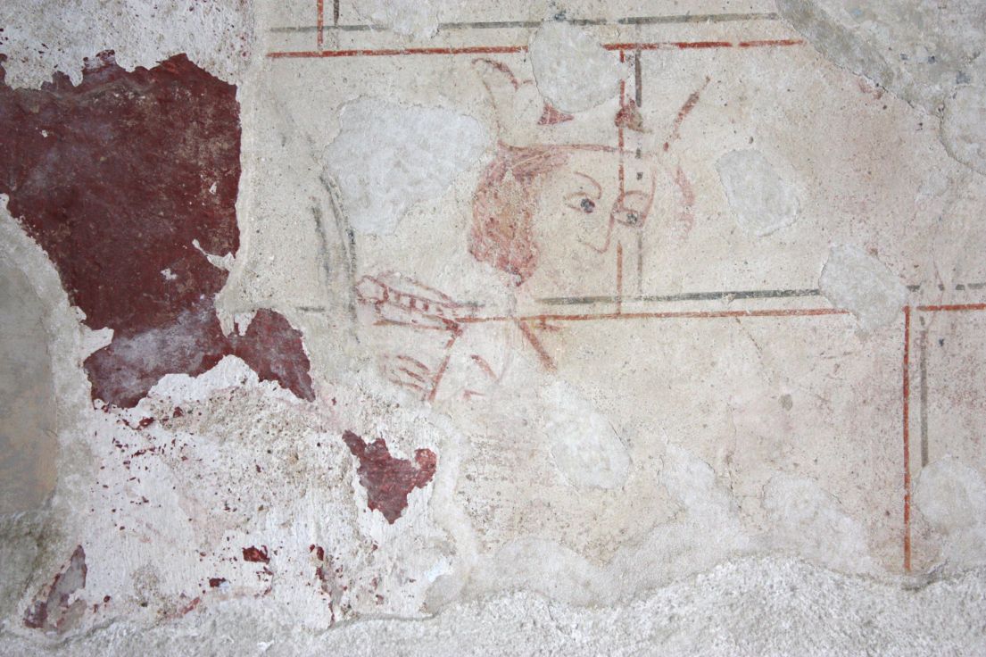 Traces of a drawing that remaining on a wall, a face wearing a crown suggests it was once a king.