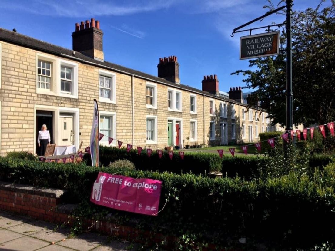 A line of stone cottage buildings, one has been turned into a museum. Outside is a HODs open day sign next to the Museum signpost.