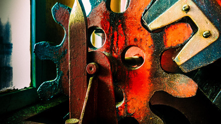 Colourful close up of a metal cog.