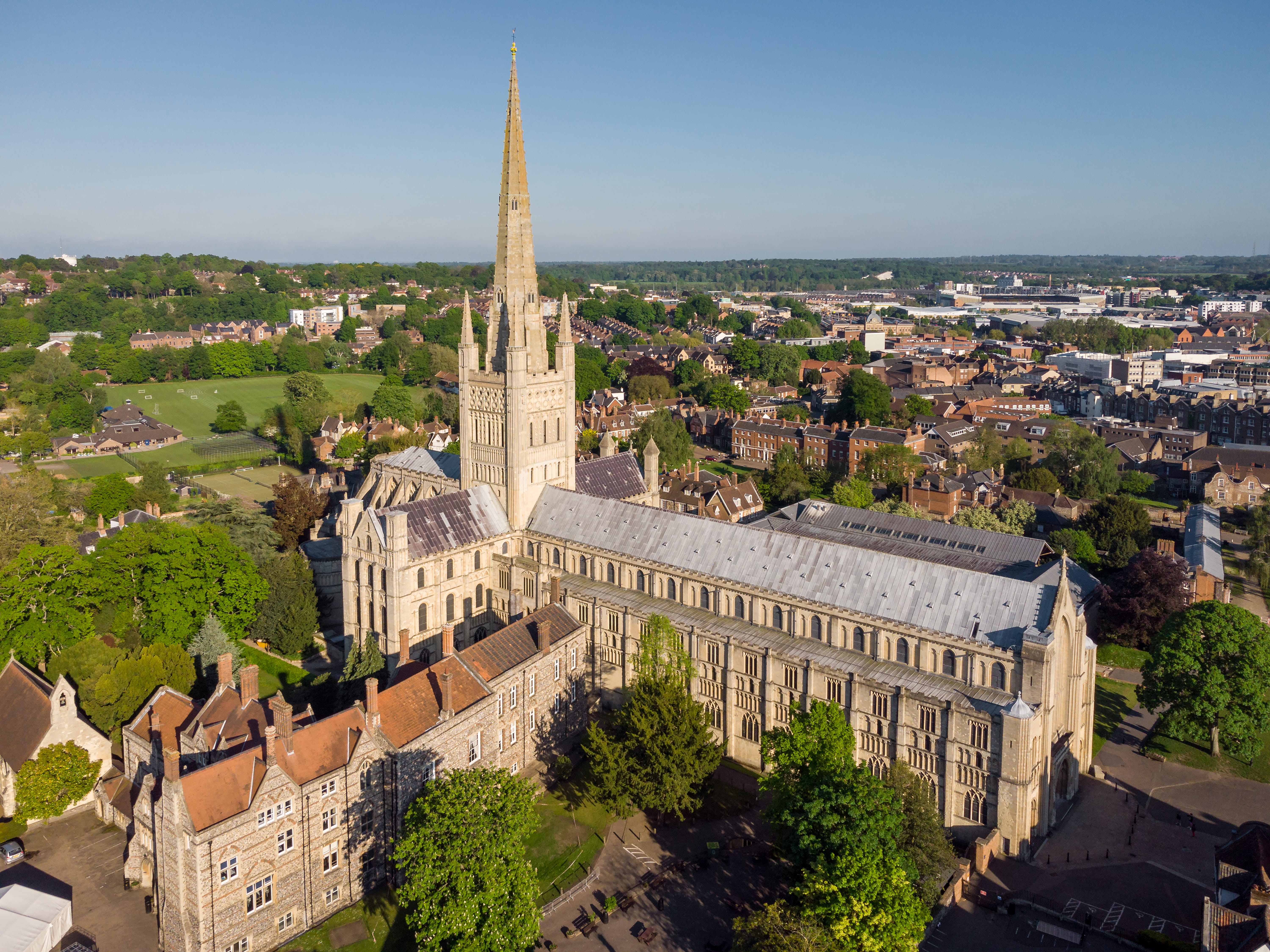 Aerial view of large cathedral with spire and the wider townscape it sits in.