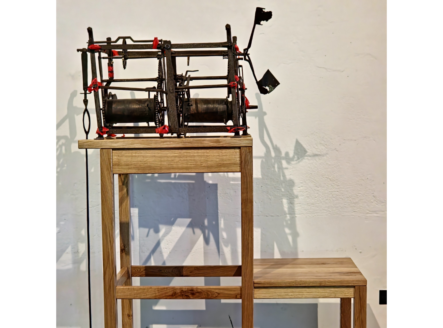 Black openwork metal mechanism on a small wooden table.