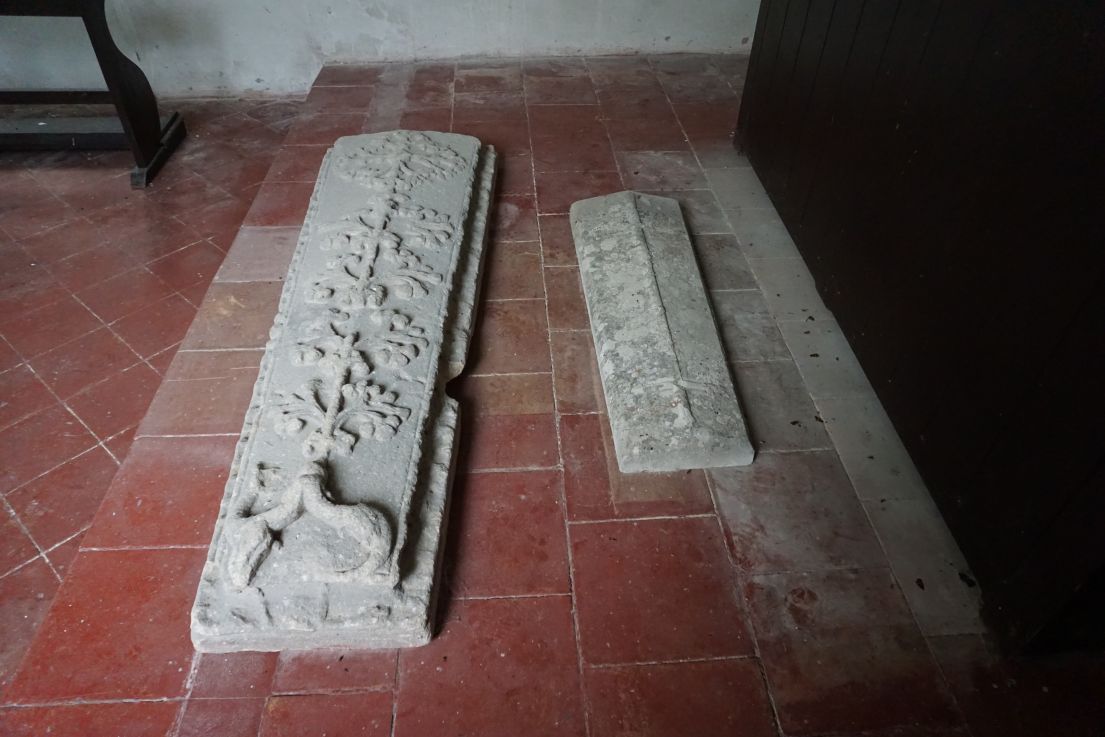 Two long decorates stone on a red tiled floor.