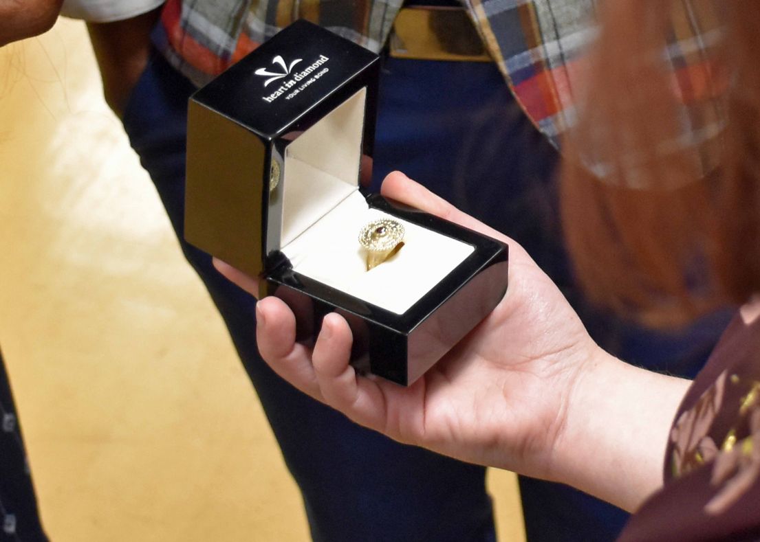A yellow gold diamond ring being held in a small black ring jewellery box. The brand reads 'Heart in Diamond.'