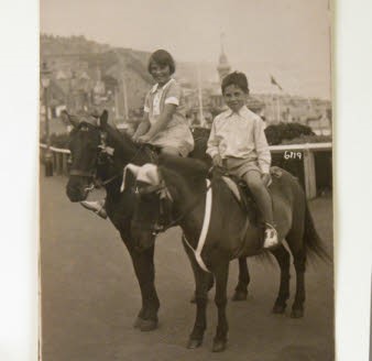 Old photograph of two children on horses at the seaside.