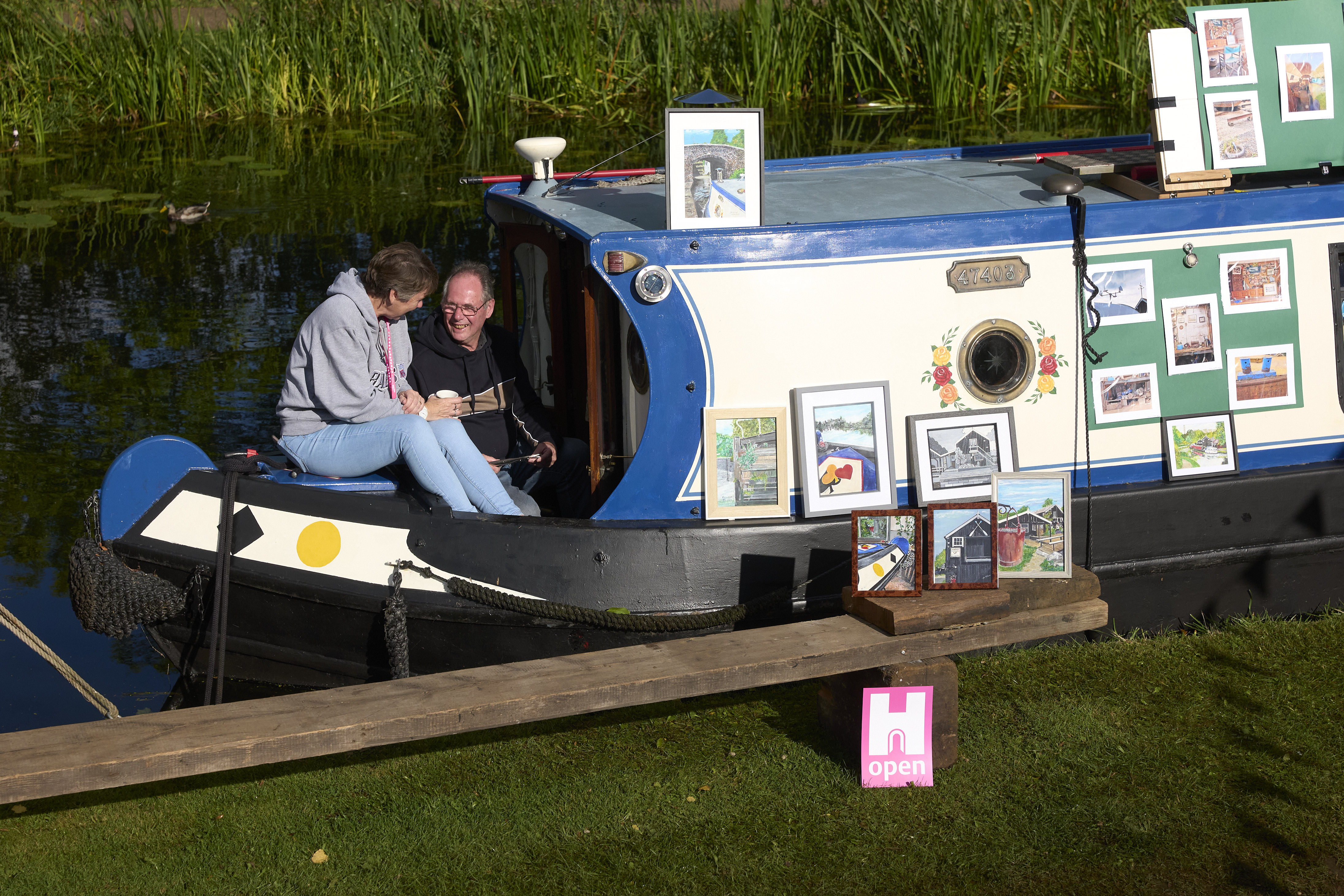 Man and woman chatting over a cup of tea at the front of a canal boat.