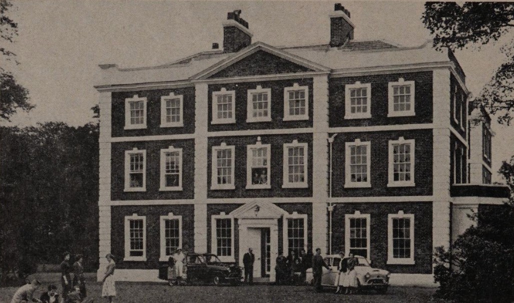 3 story brick house with porticoed door, 20 rectangular windows, and 2 sets of chimneys.