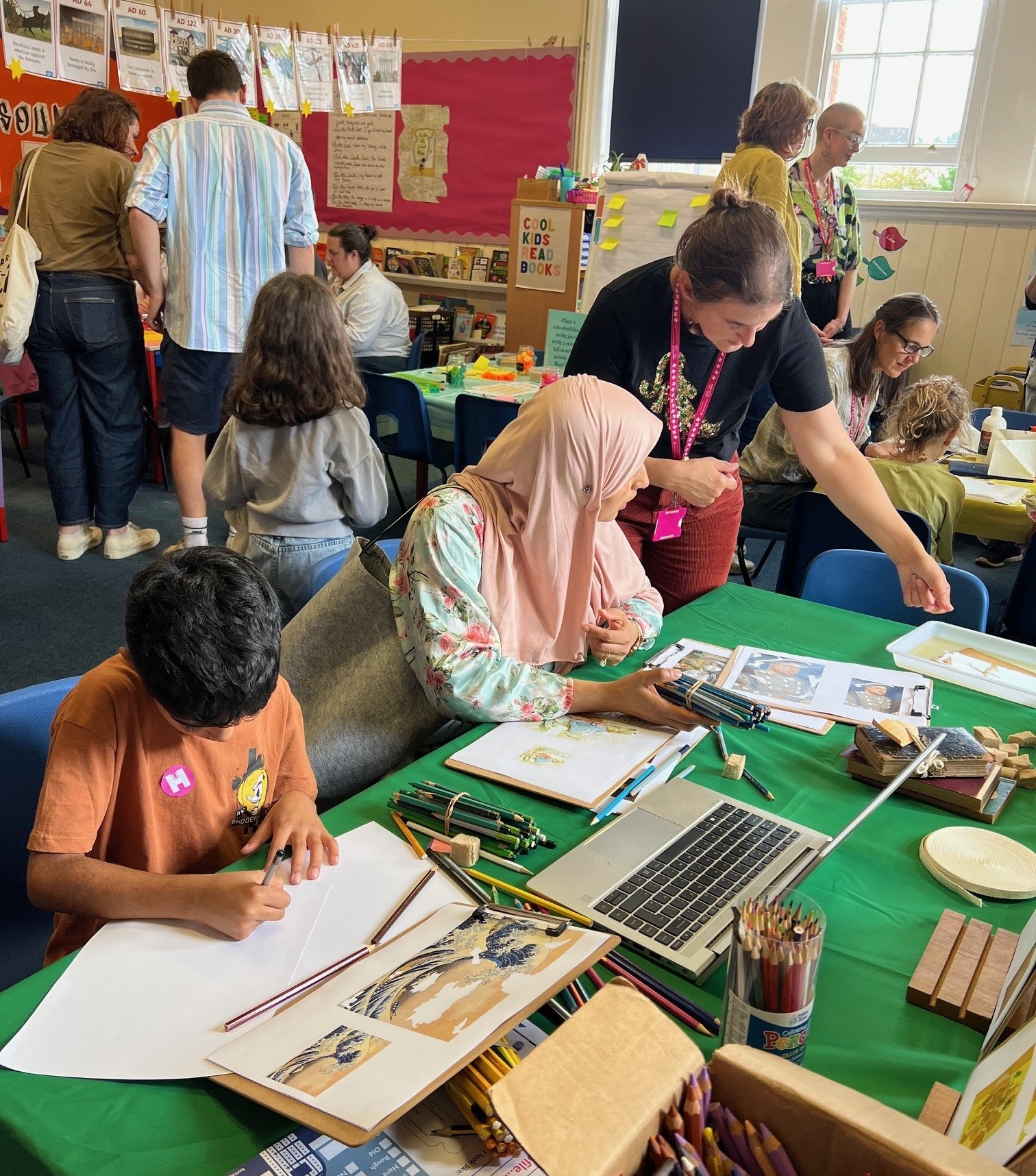 Families engaging with craft activities at tables in a classroom.