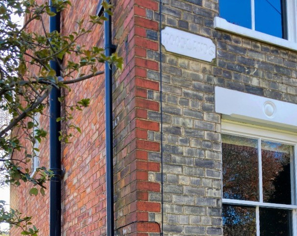 Side angle of a house, the front of grey brick, the side of red brick.