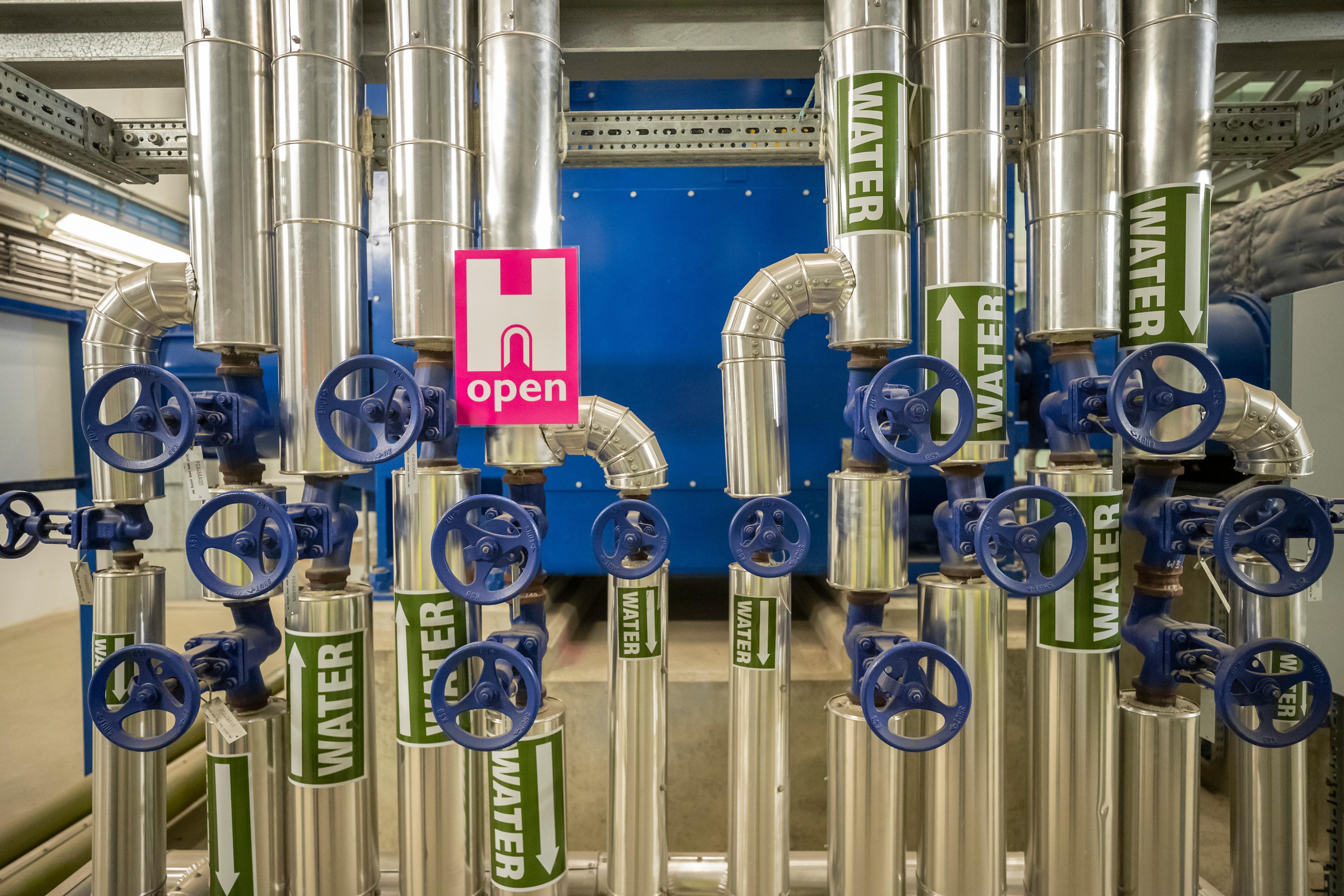 Industrial metal piles with blue wheels that open valves. A pink H Open Heritage Open Days Poster.