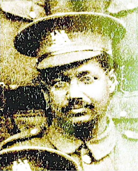 Grainy photo of man with moustache and glasses in a soldier's uniform and cap.