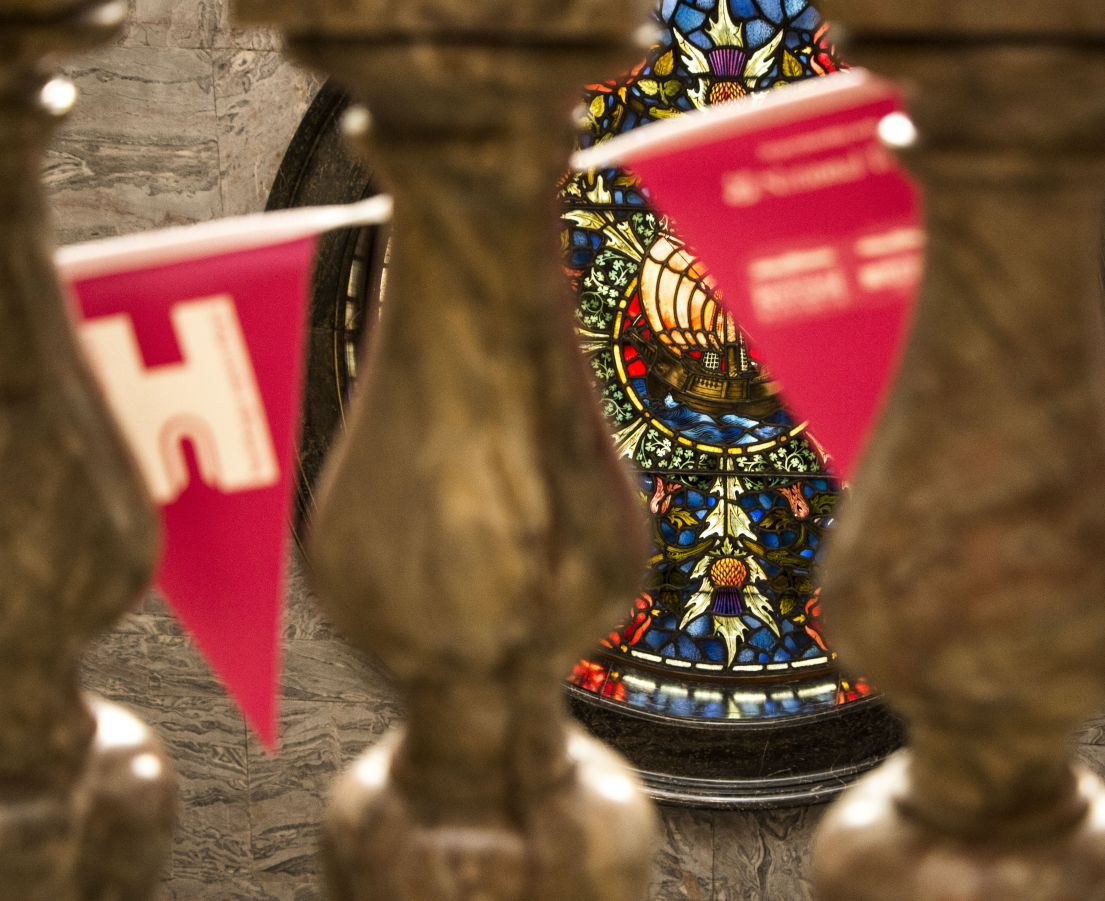 Taken through stone banisters, you can see past bright pink HODs bunting towards a circular decorated stained glass window.