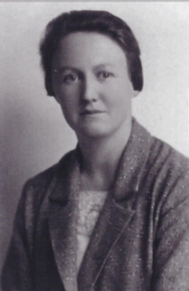 A black and white headshot portrait photograph of a women with pinned back hair.